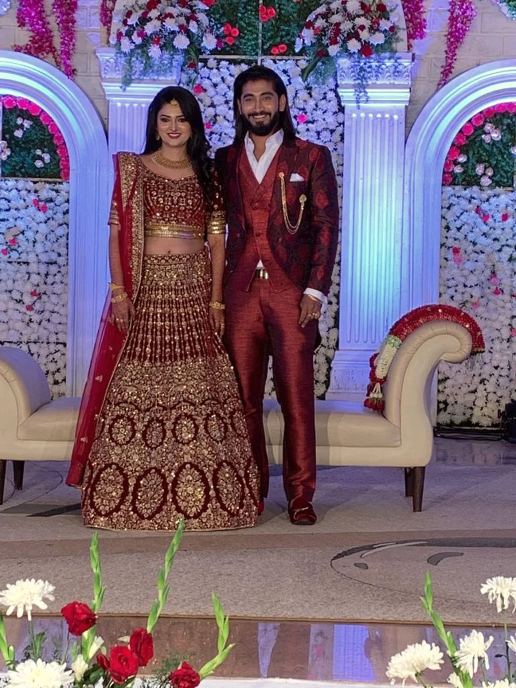 Bride and groom on the reception stage in red and gold, Anubhandhaa Bangalore