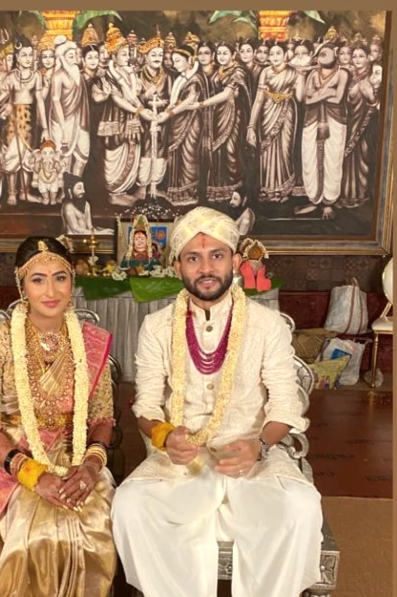 Bride and groom seated for the wedding rites before a painted mural, Anubhandhaa